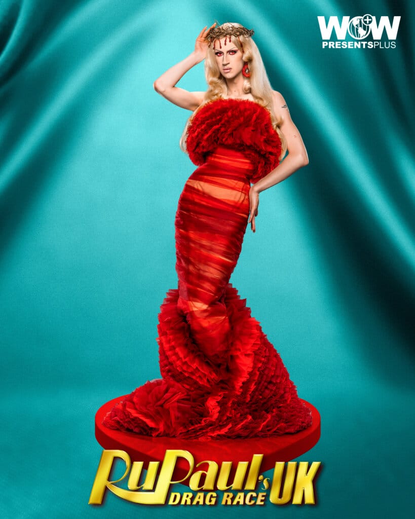 Banksie posing for RuPaul's Drag Race UK series 5 promo for Meet The Queens in a red outfit.