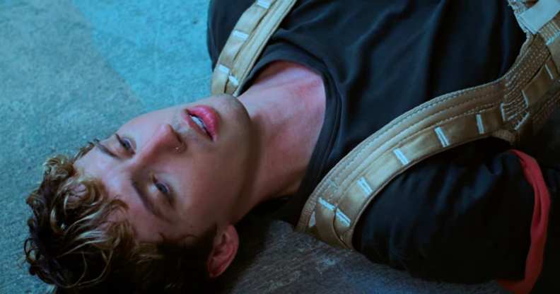 Still from "Got Me Started" music video which sees Troye Sivan harnessed up just before he flies through the air in his building ascent.