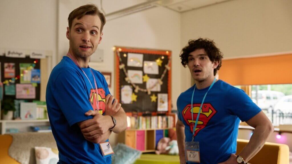 Still from "Lost Boys & Fairies" by the BBC which sees Sion Daniel Young and Fra Fee in a cafe wearing superman t-shirts.