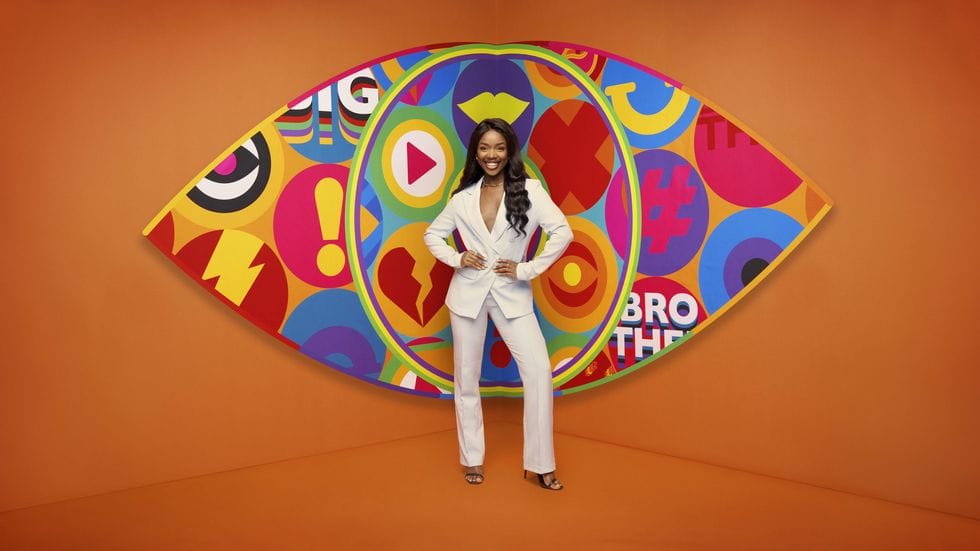 Big Brother UK 2023 Makes a Grand Comeback with Exciting New Housemates and Punishing Games 158 Big Brother 2023 housemate Noky standing in front of the new eye logo with a bright orange background.
