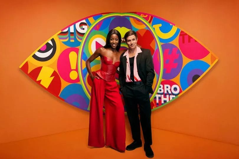 The Beginning of the End: Big Brother's 2023 Eviction: The First Exit 19 The hosts, AJ Odudu and Will Best, standing in front of the new Big Brother logo with a bright orange background. AJ is wearing a gorgeous red dress and Will is wearing a black suit with a pink shirt that is opened to show a black vest.