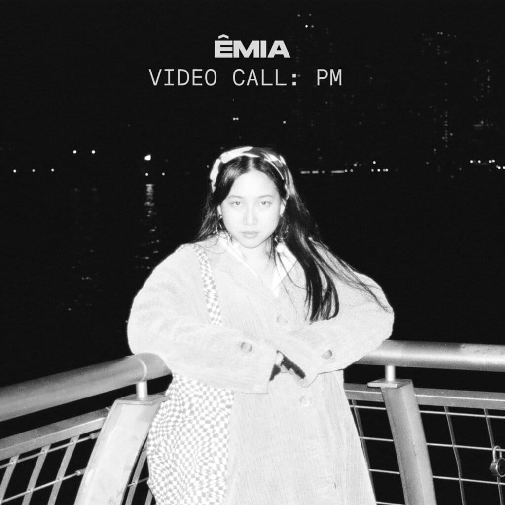 ÊMIA Unveils Sensational Sequel EP "VIDEO CALL: PM" - A Captivating Musical Journey of Emotions and Connection 67 The EP artwork for "VIDEO CALL: PM" which sees a black and white image of ÊMIA leaning back into a railing on the side of the water. The exposure is turned all the way up and she looks almost ghostly.