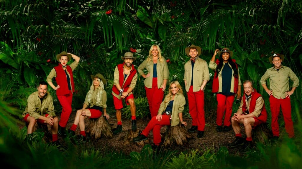 Famous Faces, Fearful Fates: I'm a Celebrity… Get Me Out of Here! 2023 Cast Has Been Revealed 69 Promotional photo for I'm A Celebrity... Get Me Out Of Here! 2023, which sees the cast of the 23rd series, all posing, in a jungle setting, wearing the camp uniform.