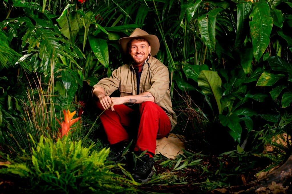 Famous Faces, Fearful Fates: I'm a Celebrity… Get Me Out of Here! 2023 Cast Has Been Revealed 68 Promotional photo for I'm A Celebrity... Get Me Out Of Here! 2023, which sees Sam Thompson in a jungle setting, wearing the camp uniform.