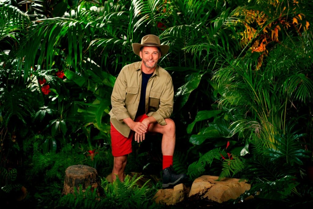 Famous Faces, Fearful Fates: I'm a Celebrity… Get Me Out of Here! 2023 Cast Has Been Revealed 66 Promotional photo for I'm A Celebrity... Get Me Out Of Here! 2023, which sees Fred Sirieix in a jungle setting, wearing the camp uniform.