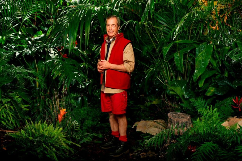 Famous Faces, Fearful Fates: I'm a Celebrity… Get Me Out of Here! 2023 Cast Has Been Revealed 60 Promotional photo for I'm A Celebrity... Get Me Out Of Here! 2023, which sees Nigel Farage in a jungle setting, wearing the camp uniform.