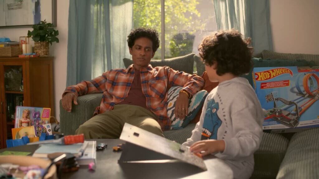 Walmart's Mean Girls Reunion with Lindsay Lohan, Amanda Seyfried, and Lacey Chabert: A Jaw-Dropping Fetch Black Friday Delight 5 Still from Walmart's Mean Girls reunion advert which sees Rajiv Surendra talking to his son in the living room.