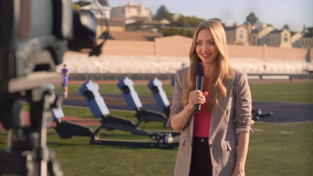 Walmart's Mean Girls Reunion with Lindsay Lohan, Amanda Seyfried, and Lacey Chabert: A Jaw-Dropping Fetch Black Friday Delight 8 Still from Walmart's Mean Girls reunion advert which sees Amanda Seyfried holding a microphone and presenting the weather.