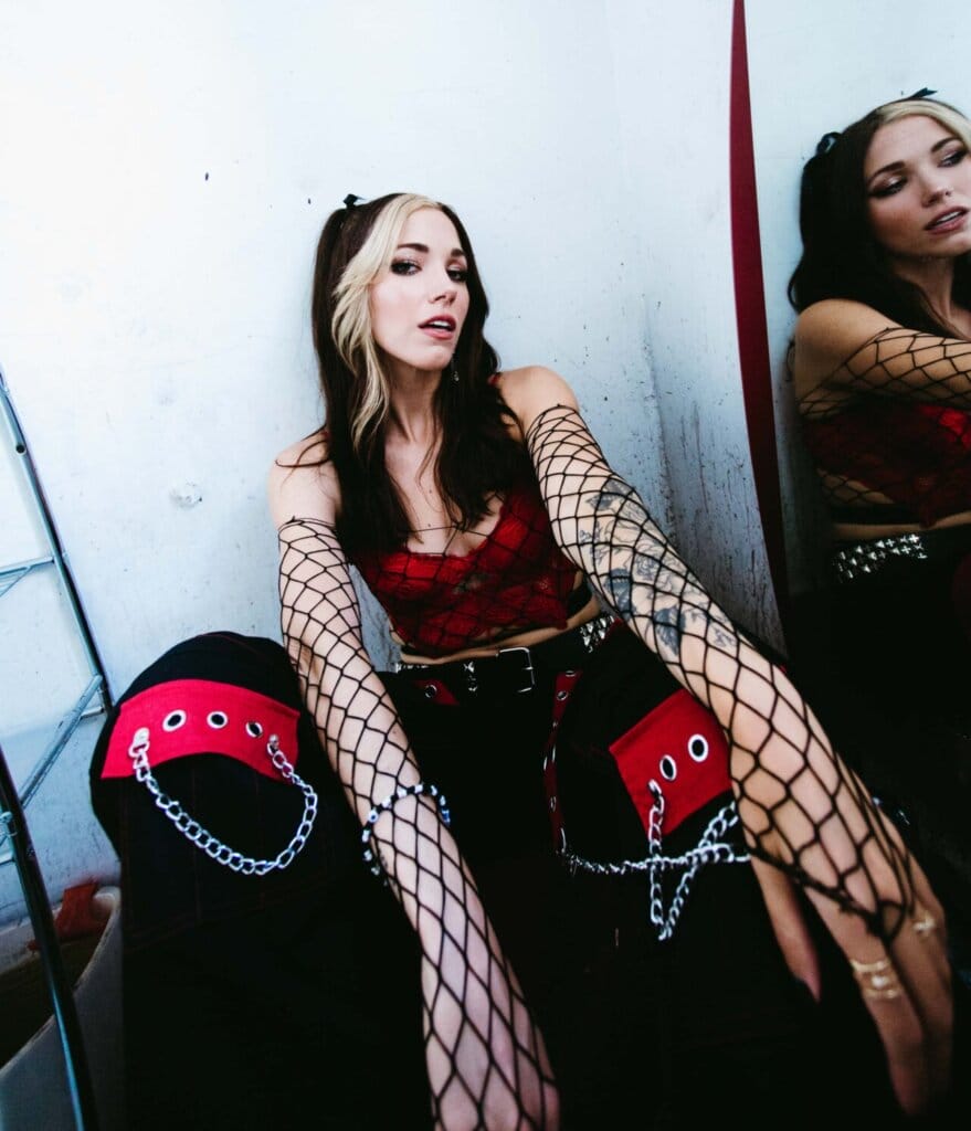 Dela Kay Unveils "IDWTAY": A Captivating Single Exploring Modern Dating Dynamics 2 Promotional photo for "IDWTAY" which sees Dela Kay posing against a mirror, wearing black and red trousers with a red bra top and she has black hair with two front blond streaks.