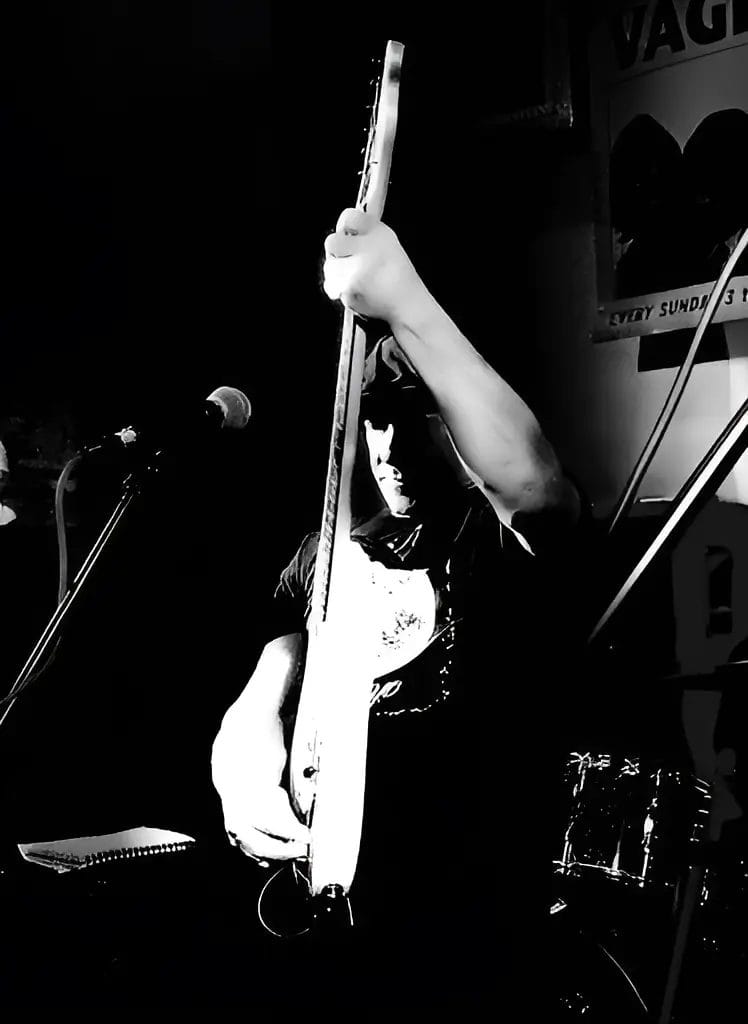 Black and white promotional photo for "Fill Up My Tank" which sees Mark Newman on stage playing his guitar.