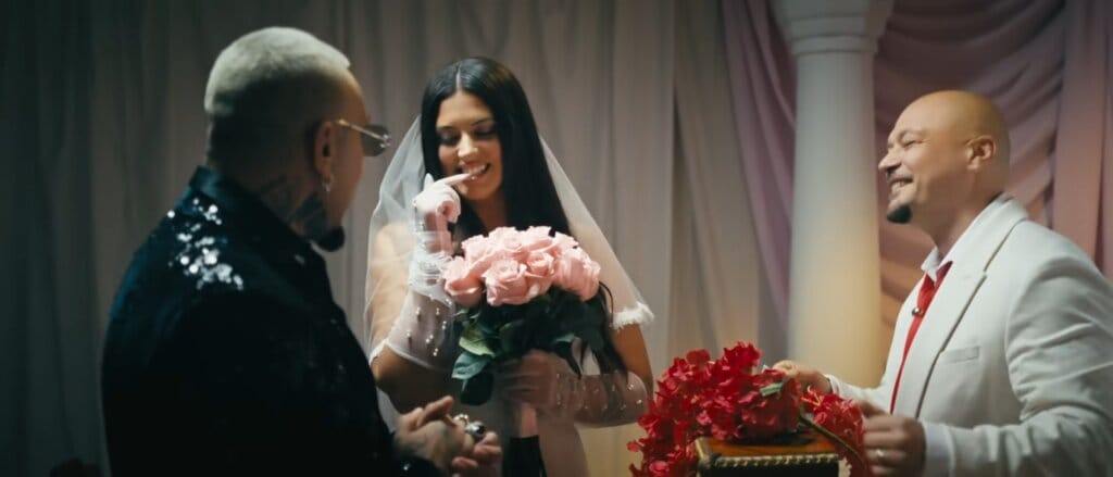 Still from the "Cum se împarte dragostea" music video which sees Antonia and Alex Velea standing at the altar while Puya is standing opposite them, officiating the wedding.