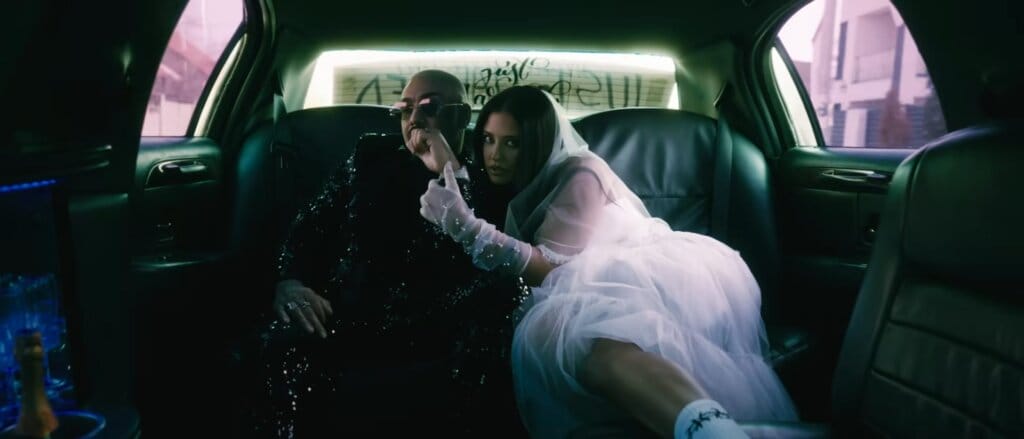 Still from the "Cum se împarte dragostea" music video which sees Antonia in a wedding dress and Alex Velea looking smart, cozying up in the back of the limo.