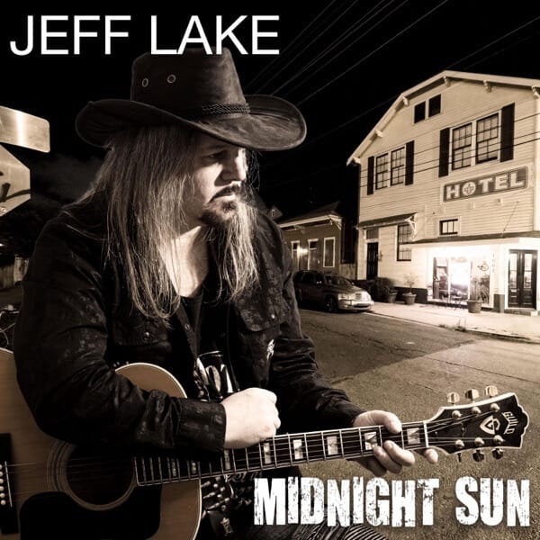 "Midnight Sun" Album Review: Jeff Lake's Genre-Defying Americana Journey Through 10 Stunning Tracks 8 Album cover artwork for "Midnight Sun" which sees Jeff Lake posing with his guitar outside and across the street from a hotel, wearing a dark jacket and a dark cowboy hat. The image has a sepia black and white filter to it.