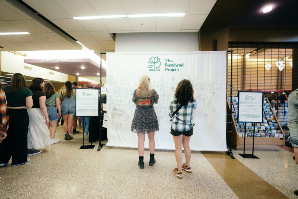 Two fans walk up to The Busyhead Project wall.