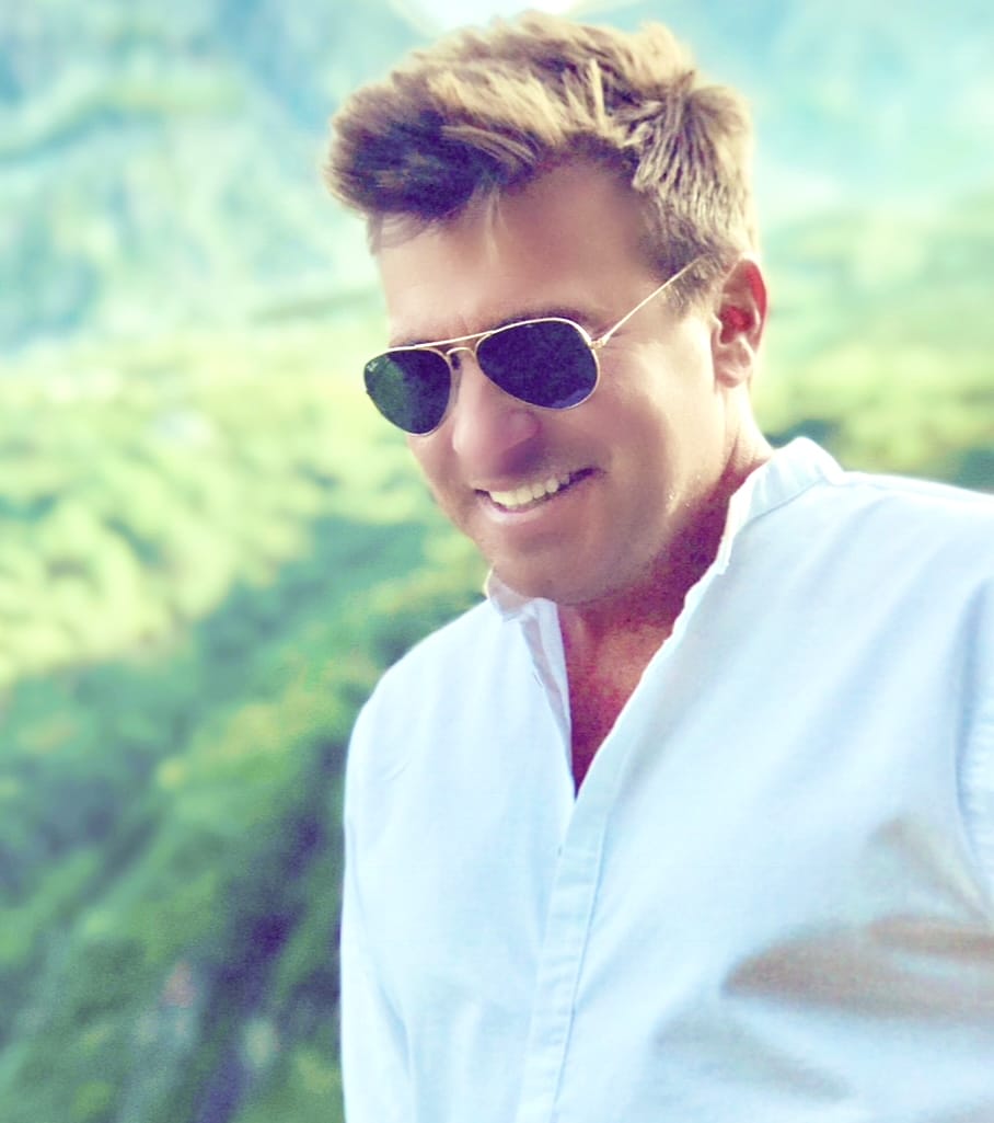 Head shot photo of Jack Maxwell wearing a white shirt and shades.