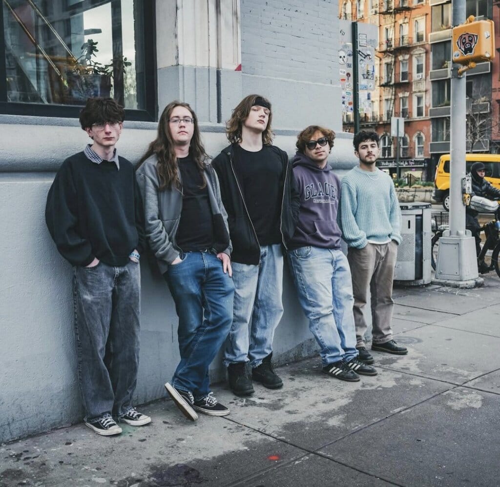 SAMSARA. Unleashes New Single "how do you say my name?" and Plans to Rock the Northeast 10 Promotional photo which sees all five band members of SAMSARA. posing against a street wall with a high window, all wearing jeans and hoodies and trainers.