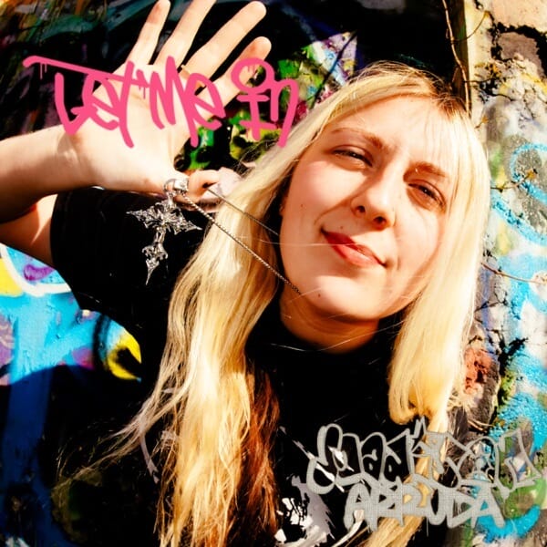 Madison Arruda Releases Dreamy New Single “Let Me In” Alongside Live Performance Video 4 Official single cover artwork for "Let Me In" which sees Madison Arruda leaning forward with her blonde hair falling past her black t-shirt. She's holding her right hand up with her thumb around her necklace.