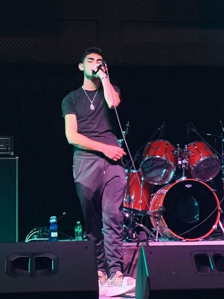 "Sunburst": Jesse Eplan Shines Bright With His Captivating New Single and Music Video 4 Jesse Eplan wearing trackies and a black shirt on stage performing one of his songs.