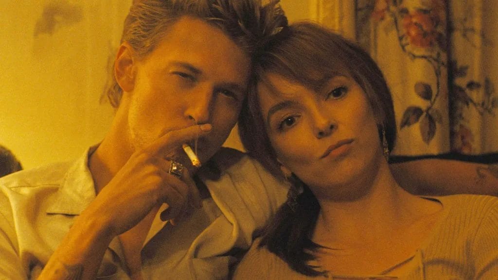 The Bikeriders Film Review: Jodie Comer Commands the Screen Through A Journey of Rebellion and Loyalty 9 Austin Butler and Jodie Comer as Billy and Kathy, cuddled up together with Billy's arm around her shoulders while he smokes a cigarette.