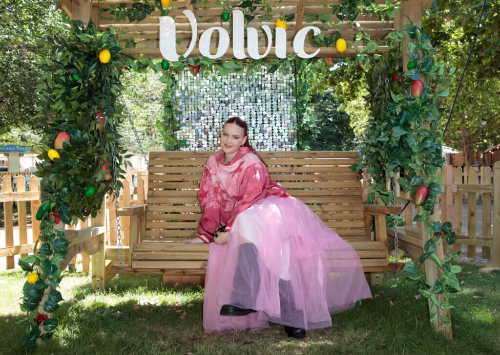 Anne-Marie posing in a pink flowing outfit on a garden swing in the Volvic HydeAway.