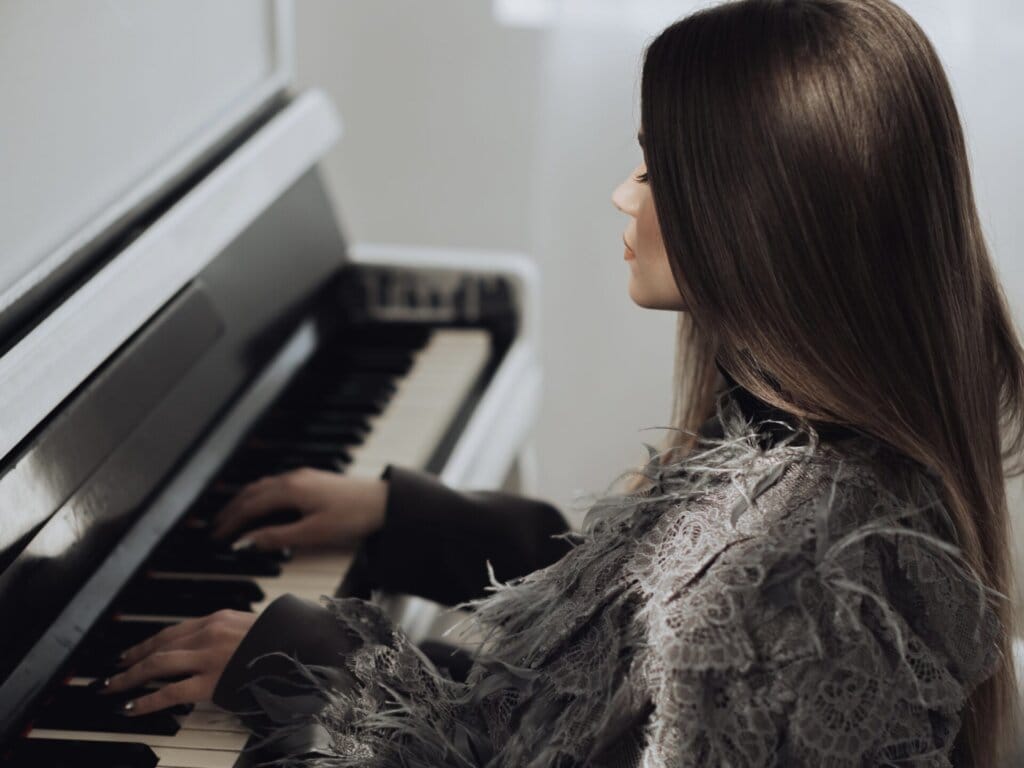 Interview: SOWA Discusses Her Music, Fashion Evolution, and Personal Growth 67 SOWA sitting at a piano with her hands on the keys.