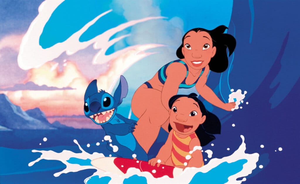 Disney Reveals First Look at CGI Stitch for Upcoming 2025 "Lilo & Stitch" Live-Action Film 45 A still from the 2002 Disney "Lilo & Stitch" film which sees Lilo, Stitch, and Nani surfing on a surfboard as a huge wave curves behind them.