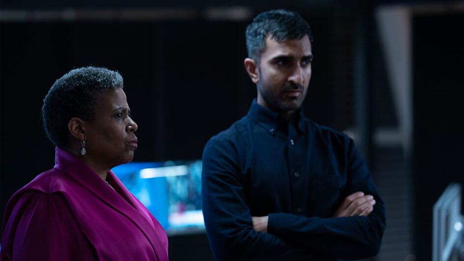 A still from the Nightsleeper trailer which sees a woman in a pink blouse (Pamela Nomvete) and a man in a dark long-sleeved shirt with his arms crossed (Parth Thakerar)