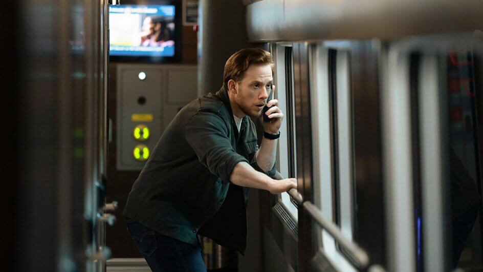 Hackjacked and Hurtling: BBC’s Nightsleeper Unveils Intense Trailer and Premiere Date 18 Still from the Nightsleeper trailer which sees a man (Joe Cole) on a brick phone, looking out a train window.