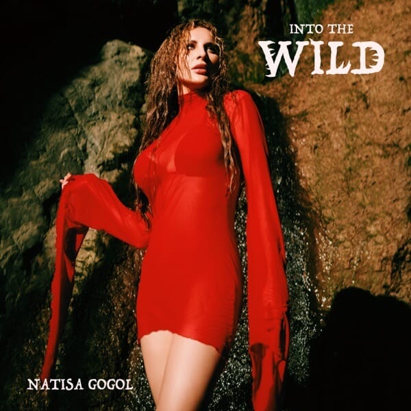 Single cover artwork for "Into The Wild" which sees Natisa Gogol leaning her back against a cave wall while wearing a see-through red dress with huge long sleeves.