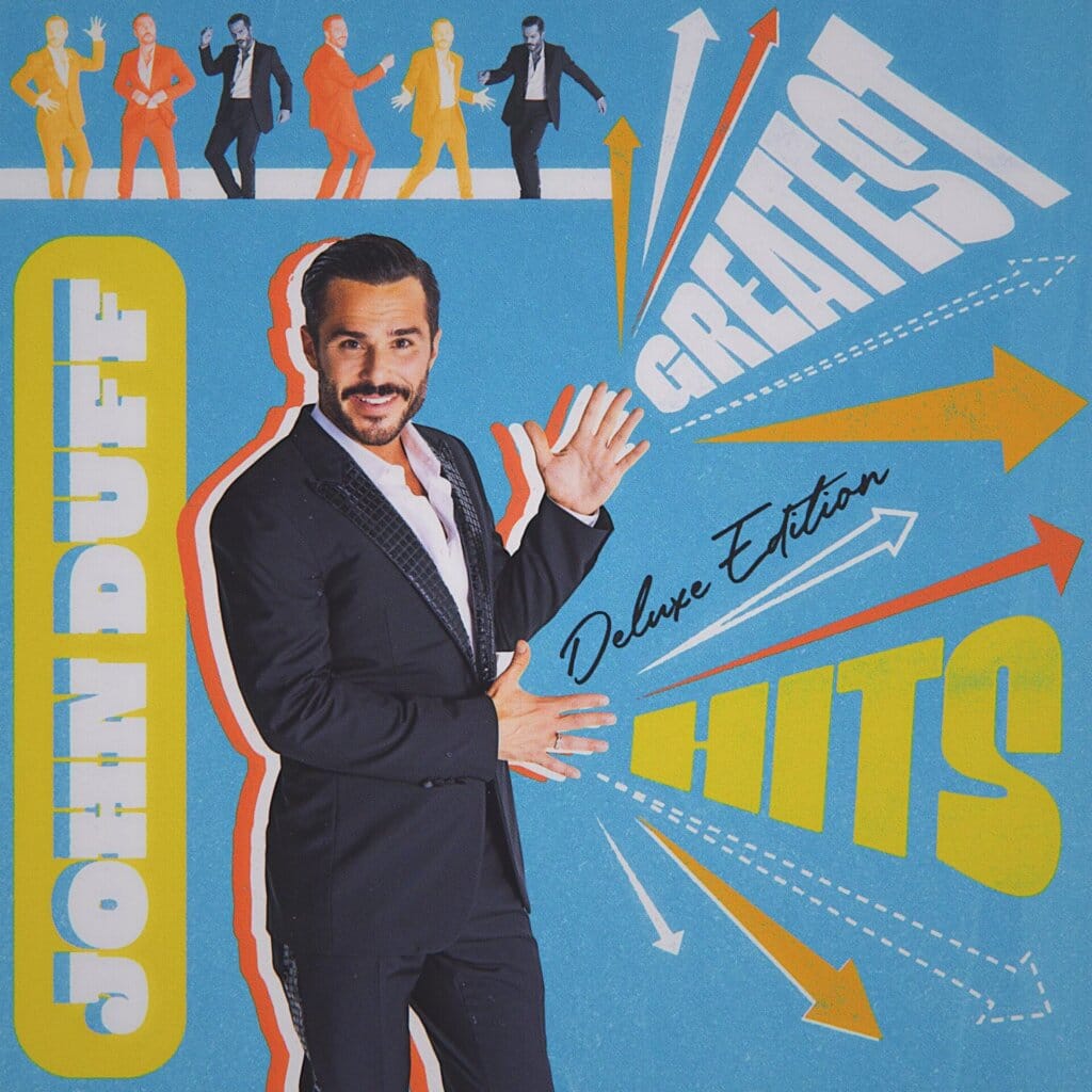 John Duff's "Greatest Hits (Deluxe Edition)" Out Now: A Playful Ode to Music's Golden Eras 2 Official album cover for "Greatest Hits (Deluxe Edition)" which sees John Duff standing with his arms out in a showmanship way, with a bright blue background and huge text of his name and the album title in yellow and white.