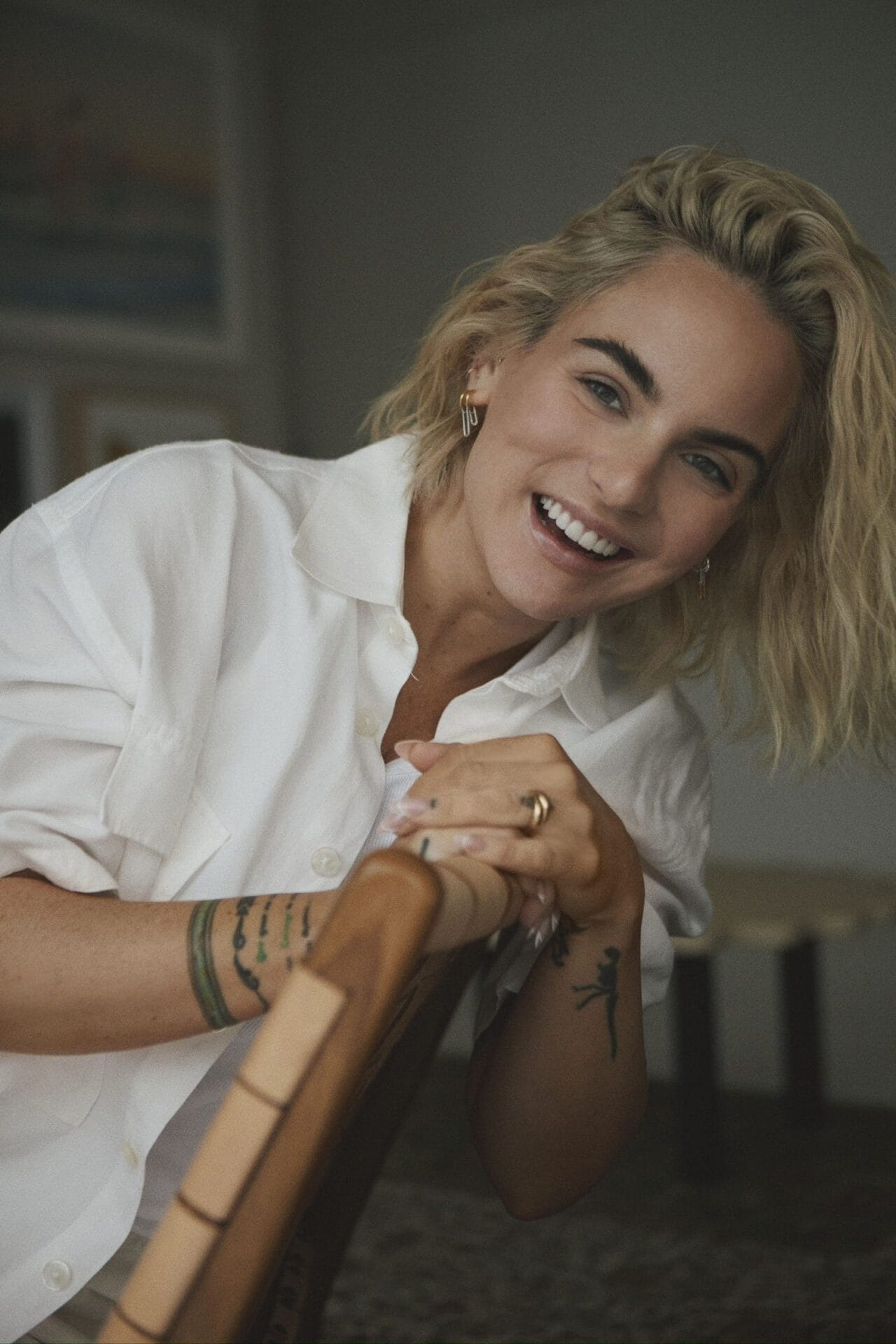 JoJo Releases Candid Memoir "Over the Influence": A Story of Triumph and Resilience 43 Official promotional image for Joanna "JoJo" Levesque's book "Over The Influence - A Memoir", which sees JoJo on a wooden chair, leaning against the back, wearing a white shirt and laughing at the camera.