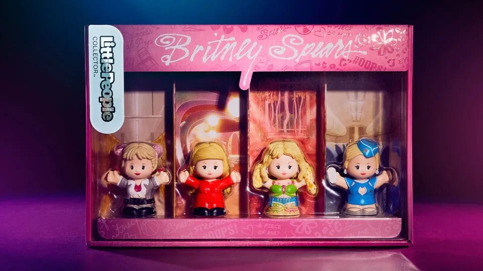 Pre-Order Now: Fisher-Price's Britney Spears Little People Set Brings Pop Icon to Life Ahead of Her Birthday 6 The Fisher-Price Britney Spears Little People figurines in their pink box with the same black background with subtle blue and pink neon lighting.