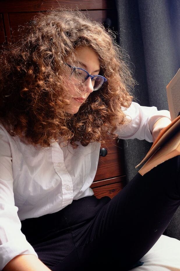 Molly McGhee's Acclaimed Novel "Jonathan Abernathy You Are Kind" Releases in Paperback 7 Official author image of Molly McGhee sitting down, reading a book, wearing a white shirt, black trousers, and a pair of glasses.