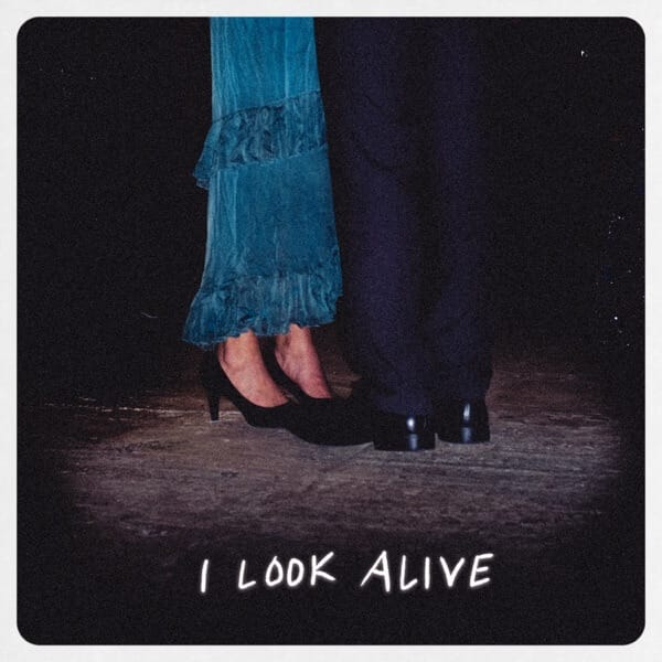 Phoneboy Returns With Brand New Single "I Look Alive" Alongside a Halloween-Inspired Music Video 2 Official single cover artwork for "I Look Alive" by Phoneboy which sees two pairs of legs facing one another on a street, one is a woman's legs wearing a pair of jeans and some black high heels, whereas the other pair of legs is wearing navy trousers and black shoes.