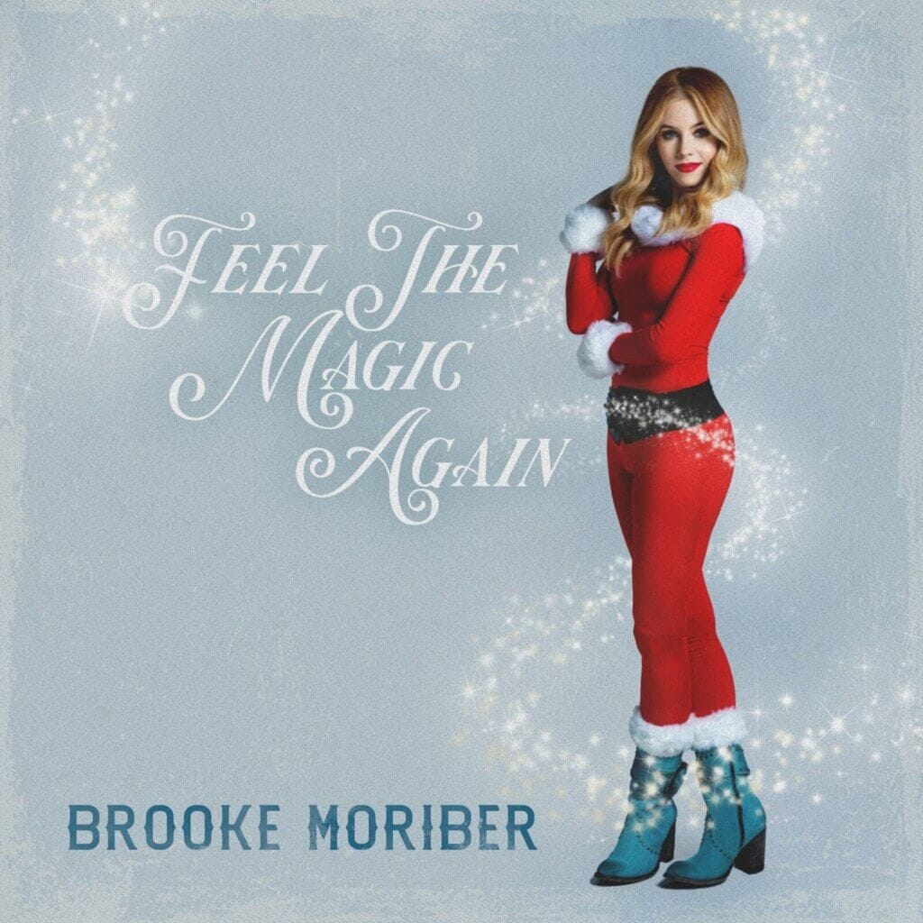 The single cover artwork for "Feel The Magic Again" which shows a wintery cover with Moriber dressed in a red bodysuit giving Mariah Carey vibes.