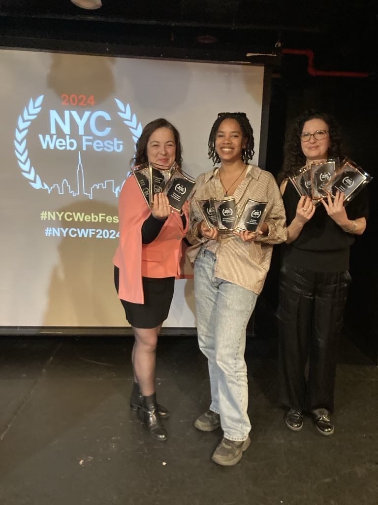 NYC Web Fest 2024 Award Winners: Celebrating the Best in Digital Storytelling with Award-Winning Web Series, Short Films, and Pilots 40 Marie-Hélène Lebeau Taschereau, Nadia Louis-Desmarchais and Marie-Élène Grégoire holding awards that their shows have won, in front of a screen with the NYC Web Fest 2024 logo on it.
