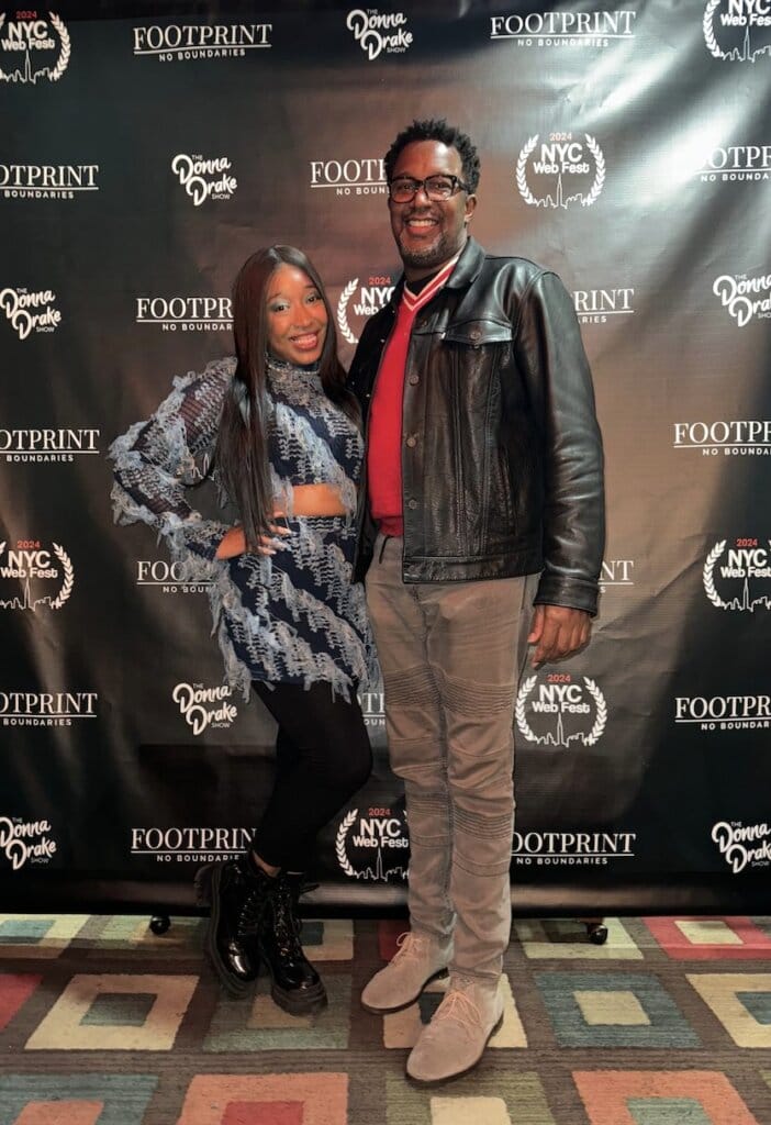 NYC Web Fest 2024 Award Winners: Celebrating the Best in Digital Storytelling with Award-Winning Web Series, Short Films, and Pilots 38 Cylla Senii & Rick Younger posing in front of the NYC Web Fest logo banner which also has Donna Drake and Footprint Network logos on.