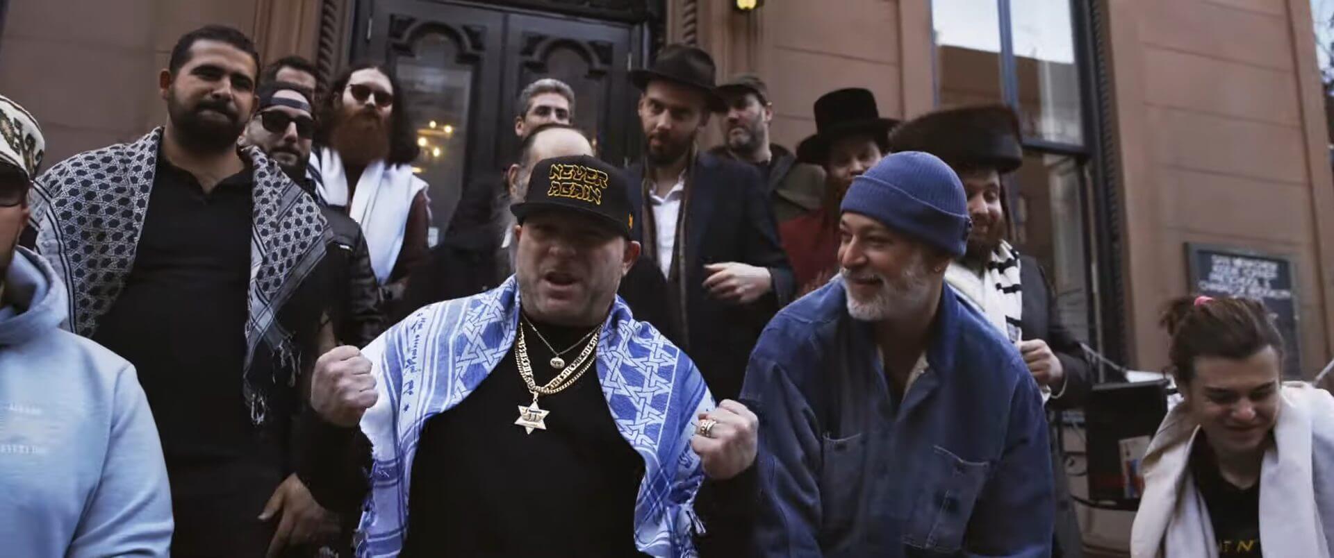 A still from the music video of "The Fathers Live" which sees Matisyahu and Remedy performing together outside a New York Synagogue.