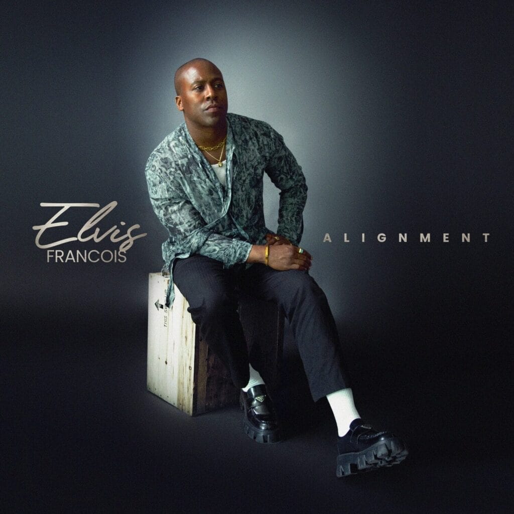 Official EP artwork for "Alignment" which sees Elvis Francois wearing a grey shirt and black trousers with black trainers and white socks, sitting on a metal grey box, against a black background. He is silhouetted by a white light.