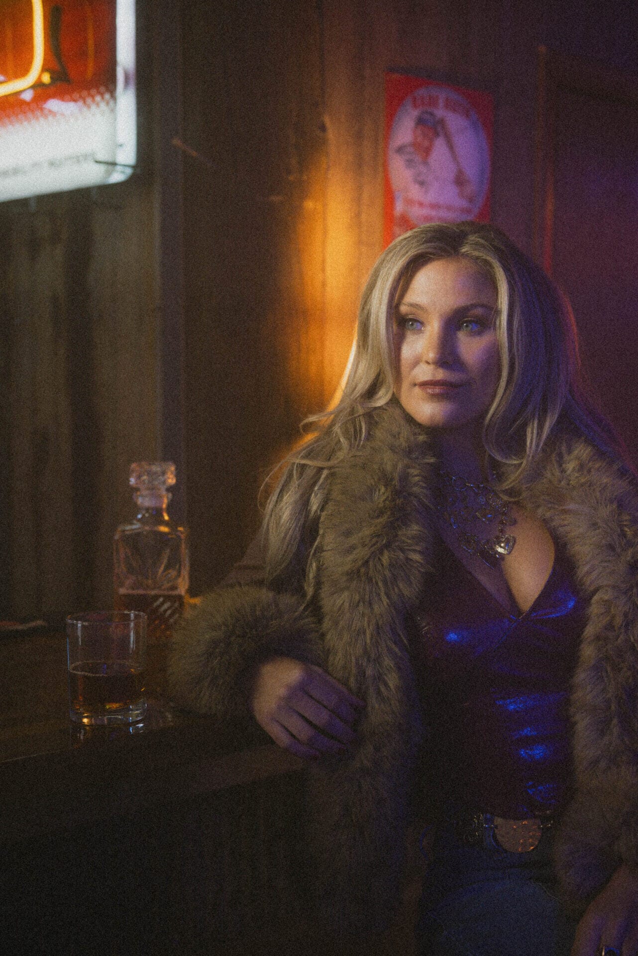 "Heartbreaker": Karissa Ella Celebrates Strength and Self-Rediscovery in New Single 12 Karissa Ella posing with a fur coat on that is opened to reveal a navy top and jeans. She's posing next to a whiskey decanter with a glass of whiskey on the table she's resting her arm on.