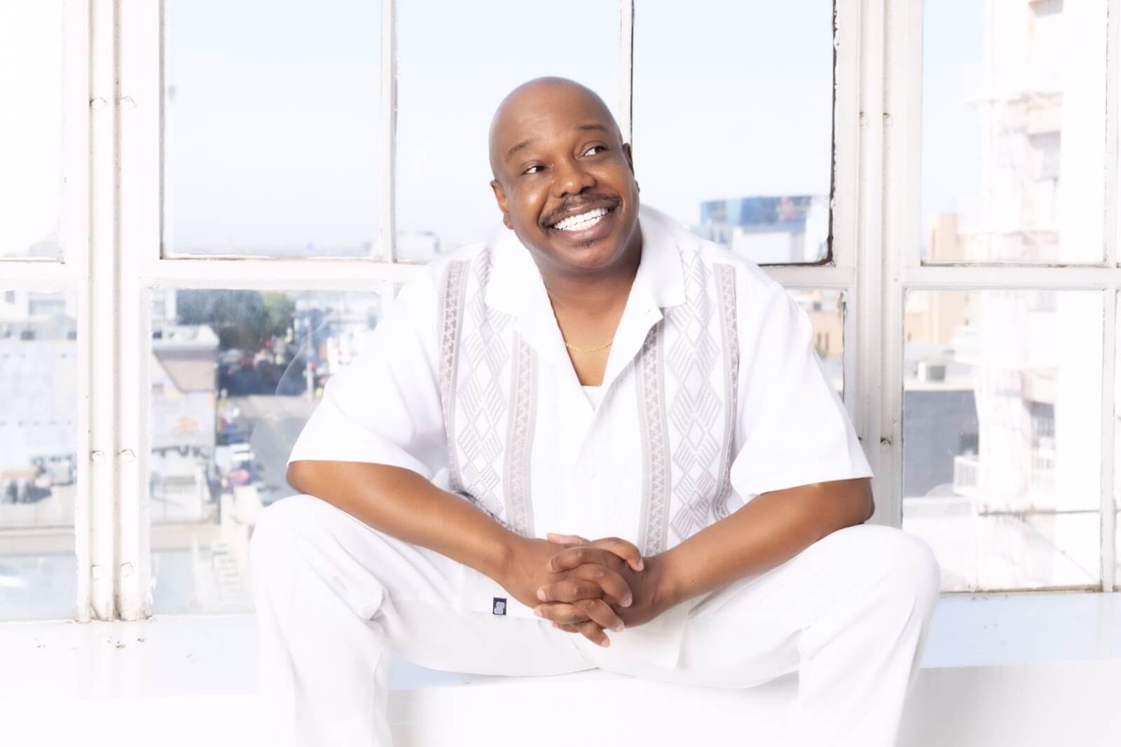 Kenneith Perrin sitting on a window ledge dressed in white.