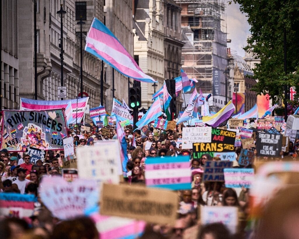 London Trans+ Pride 2025: Powerful Celebrity Messages Echo the Theme "Existence & Resistance" 106 London Trans+ Pride 2024 crowd marching together with trans flags, banners, placards, and signs.