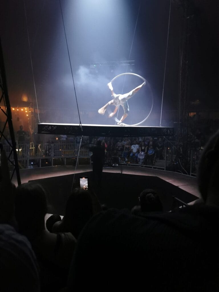 A woman on a raised platform performing with a Cyr Wheel.
