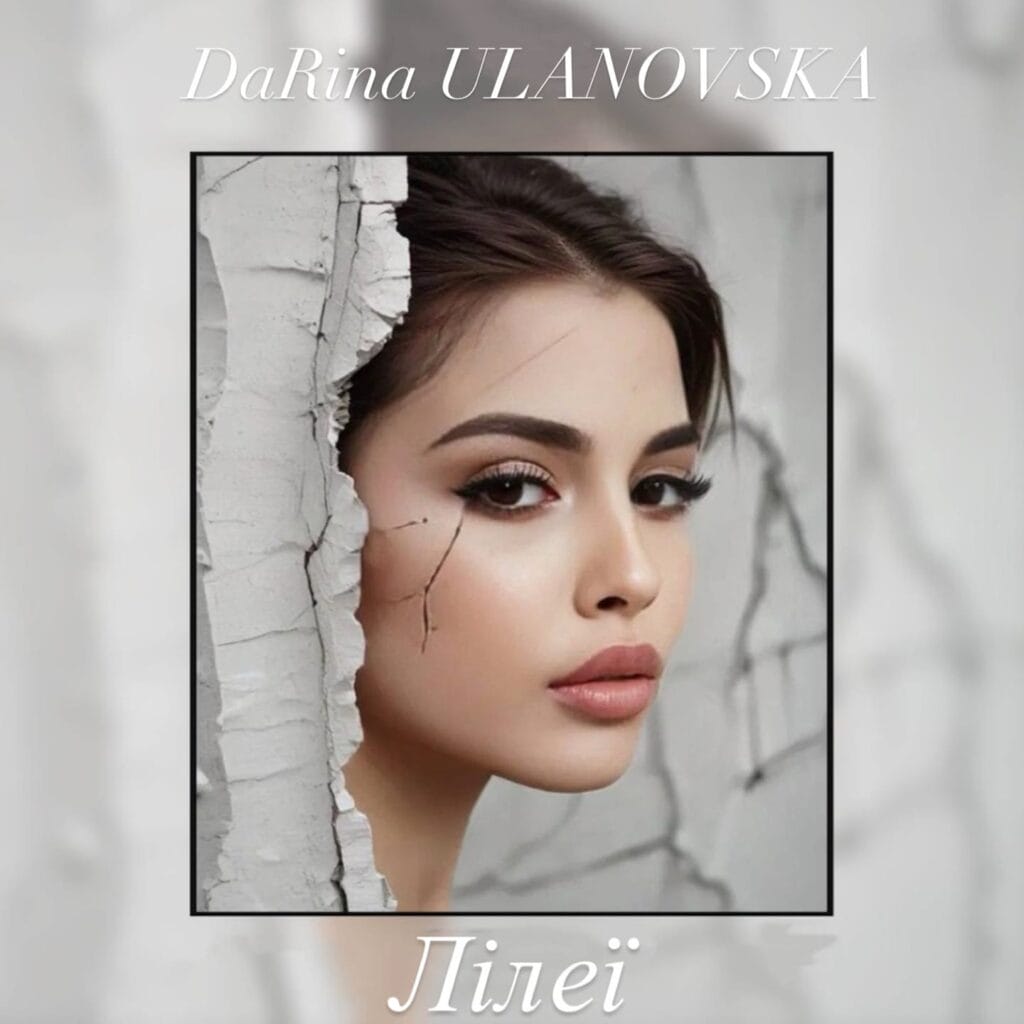 Official single cover artwork for “Лілеї" Meaning “Lilies” which sees DaRina Ulanovska peering around a wall with her hair tied back. The image is framed by a small black border ant then the outer edges are blurred.