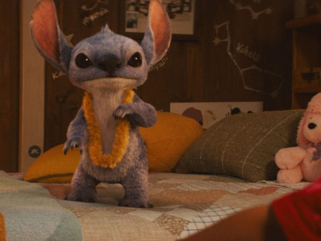 Film Review: Disney’s Lilo & Stitch (2025) Is a Nostalgic Journey That Will Make You Laugh, Cry, and Believe in ‘Ohana All Over Again 68 Stitch standing on Lilo's bed wearing an orangey-yellow Hawaiian lei flower necklace.