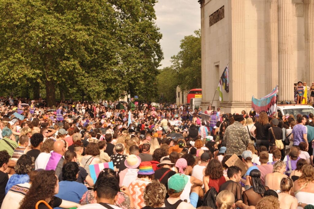 A crowd of trans rights protesters holding up banners and signs.