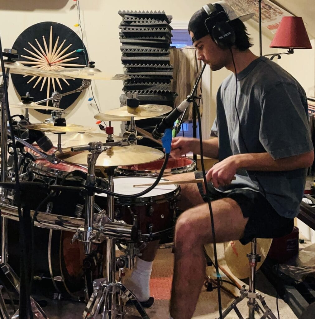 Merit Maker Delivers Honest Punk Energy with New Album "Better Days Ahead" 4 Official press photo of Blaise Rantanen playing the drums in shorts and a grey tee.