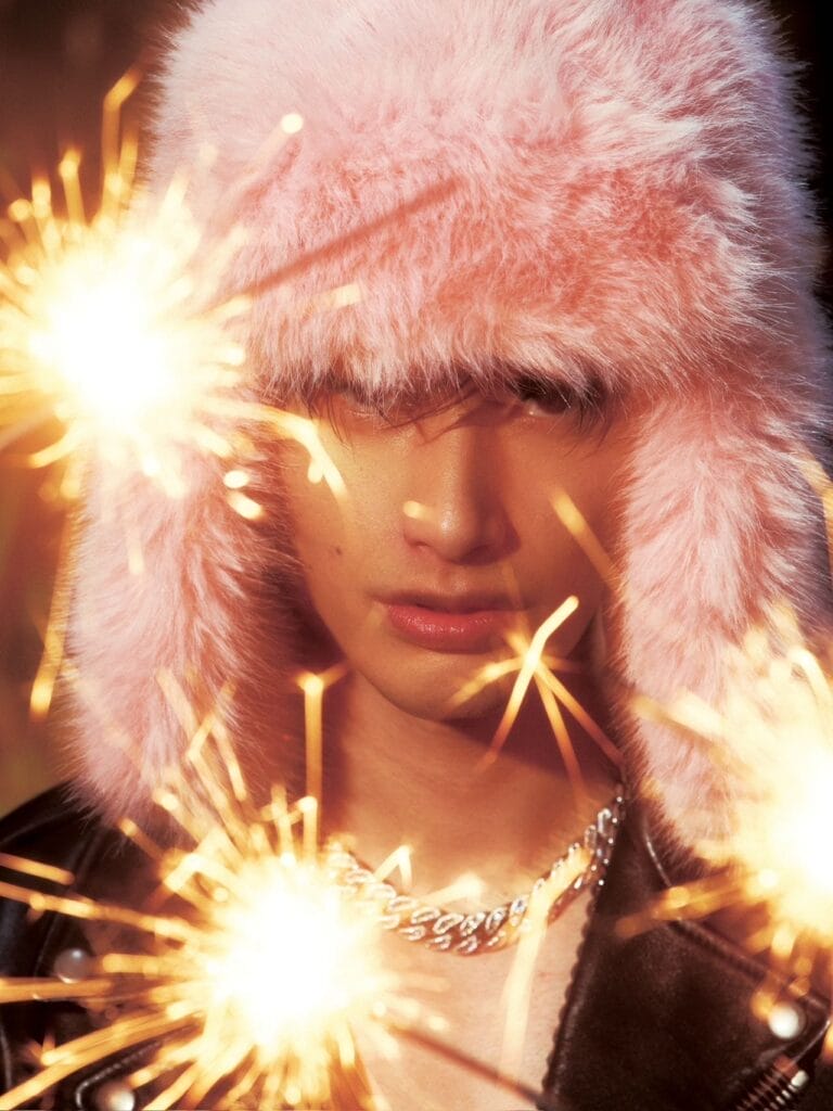 BENZO Returns with Powerful New Album "MAMA, I’M BACK": A Bold Statement on Chinese Hip-Hop’s Global Rise 4 BENZO wearing a pink fluffy hat that covers most of his head, with three sparklers in the foreground, lighting up the image.