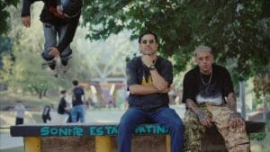 Still from the "La Calle Quema" music video which sees Victor Vildósola who leads THEKOIWAY sitting next to Jamez Manuel at a skate park.