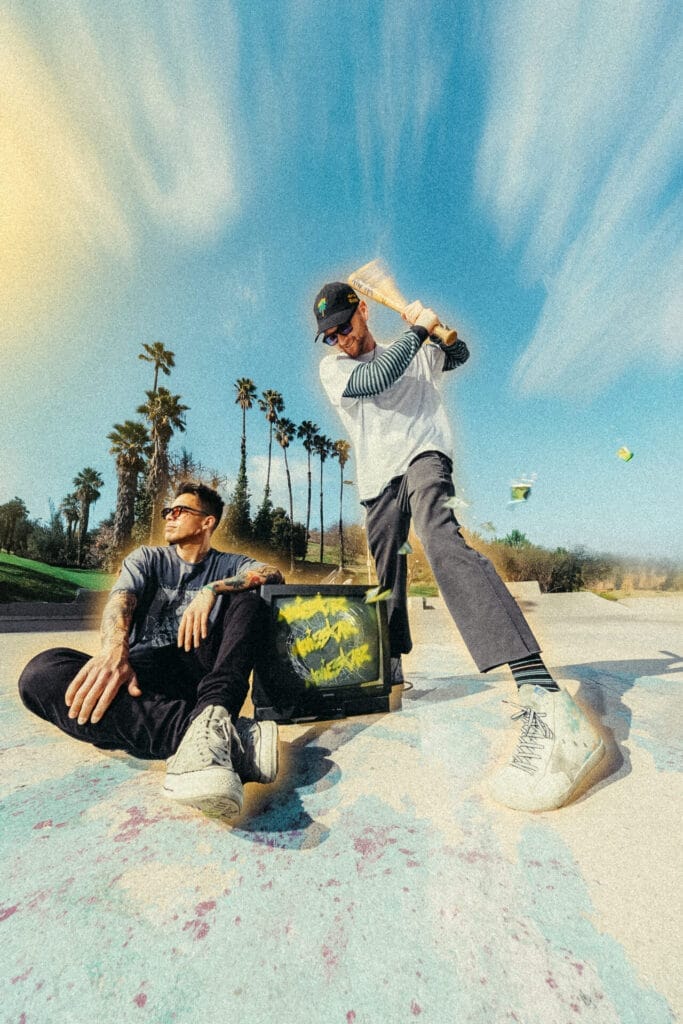 Double Trouble: MOVIESTARZ Drop Glitchy Bangers “Chaos in the Magic” and “Tear This Apart” 17 Official full-length version of the duo, MOVIESTARZ, on the beach with palm trees in the background. One of the guys is sitting on the sand with an arm on a TV that has graffiti on, and the other member of the duo is standing up who is about to swing a baseball bat down over his head.